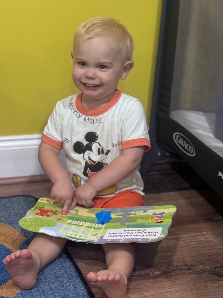 Smiling toddler with a picture book at CB Children's Academy