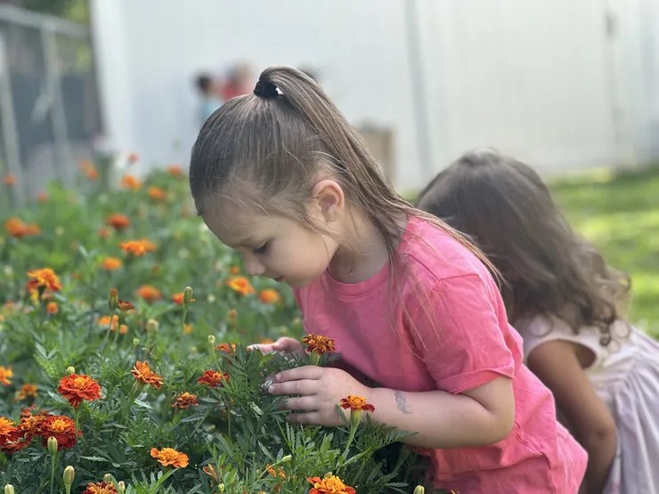 Girl smelling marigolds in the CBCA community garden