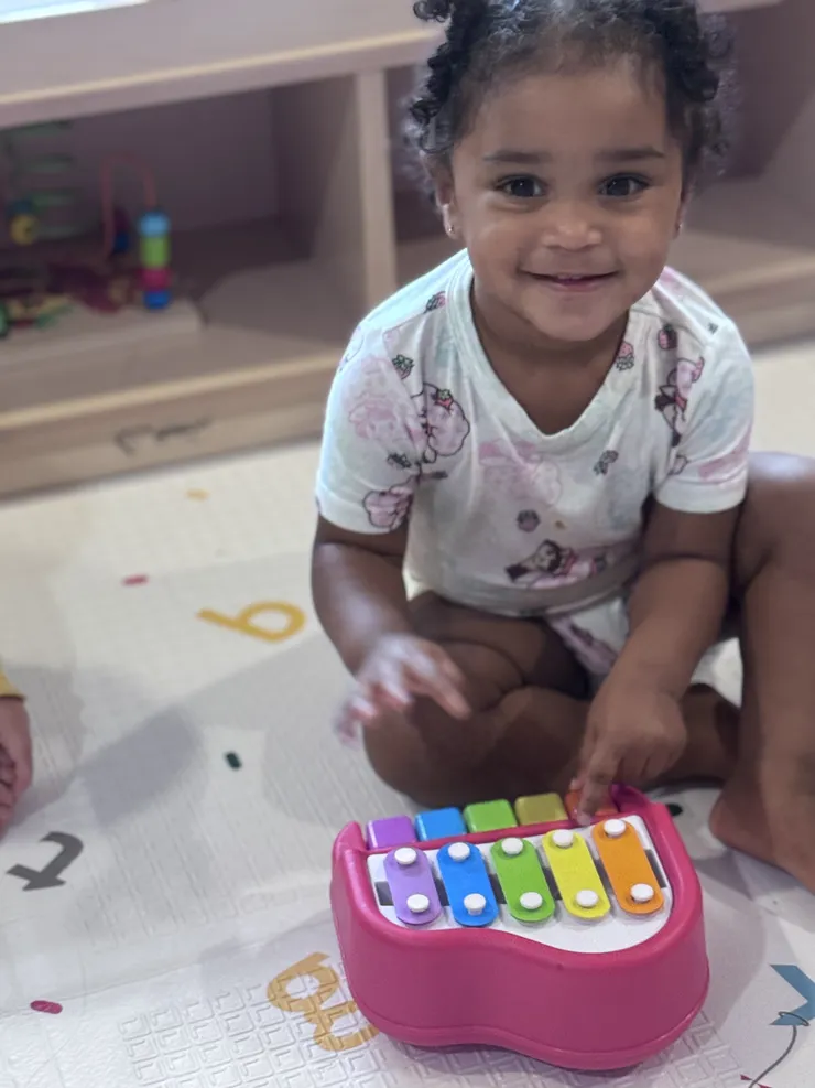 Toddler playing a colorful xylophone at CB Children's Academy